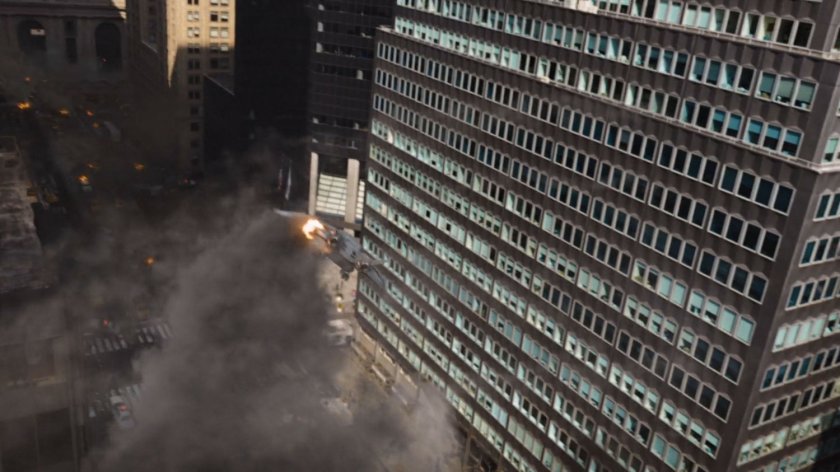 A smoking quinjet descends towards a large office building.