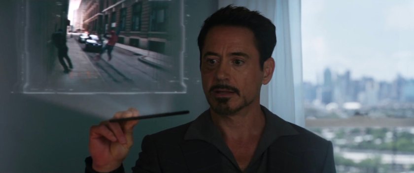 Tony Stark showing a holographic video of Spider-Man swinging down street.