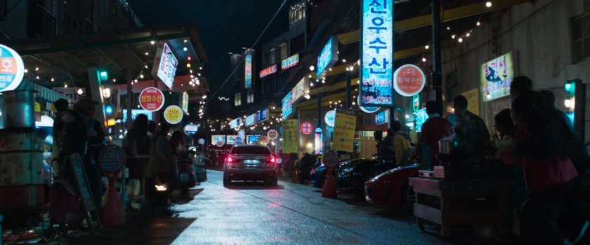 a car driving through a Busan alley/market.