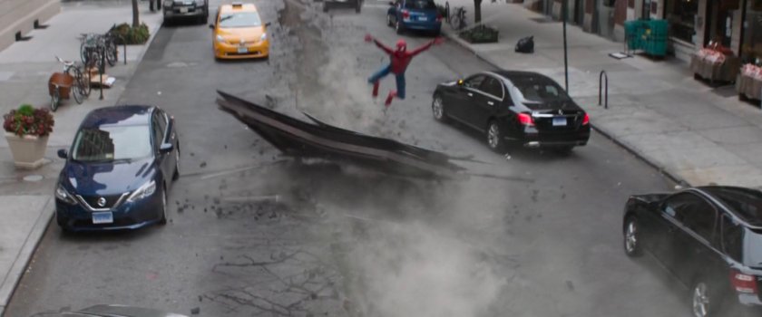 Spider-Man leaping over debris that lands in a New York street.