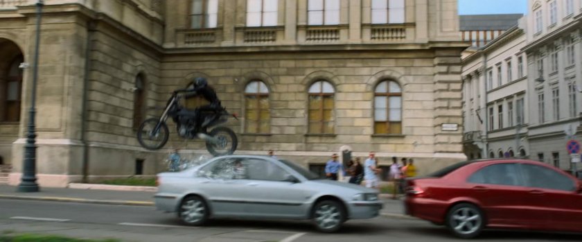 A motorcycle jumps over a small car on a Budapest street.