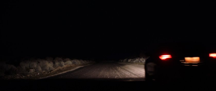 Nighttime shot of car on desert road.